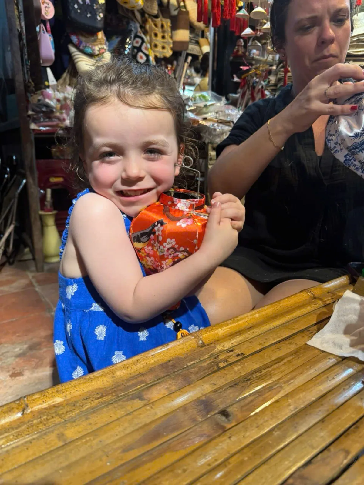 Child holding a handmade silk lantern at a family-friendly Hoi An lantern class