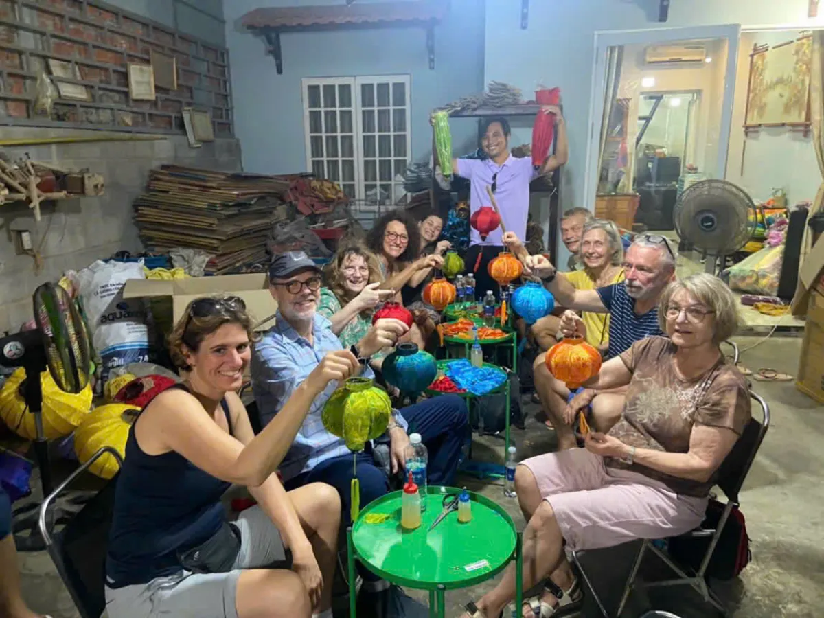 Travellers holding up the silk lanterns they made in Hoi An