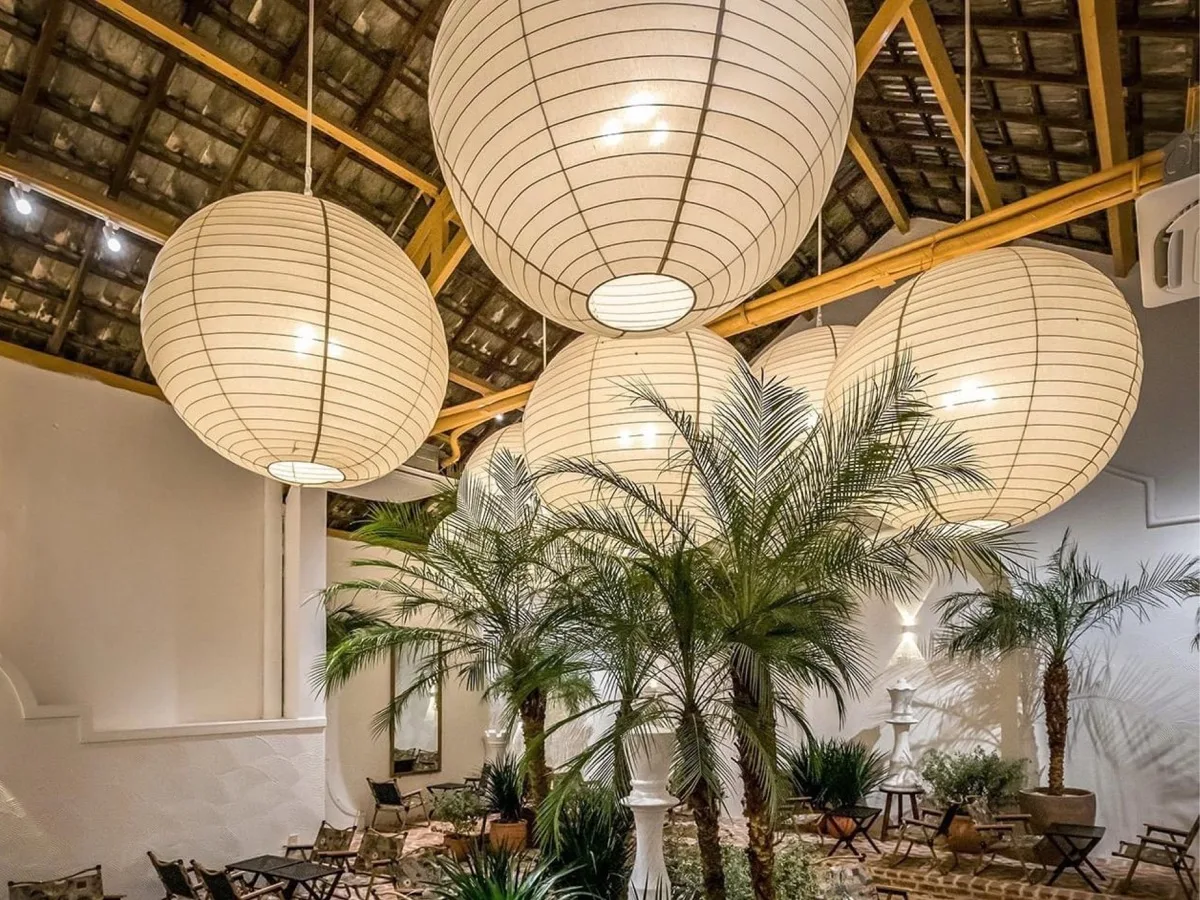 Đèn thả trần hình cầu trắng tại resort ngoài trời với cây xanh